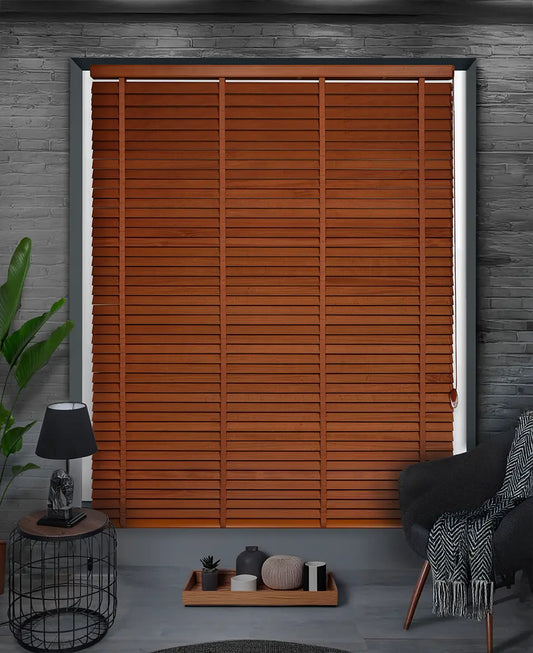 Wooden blinds in a room with a lamp, plant, and chair.